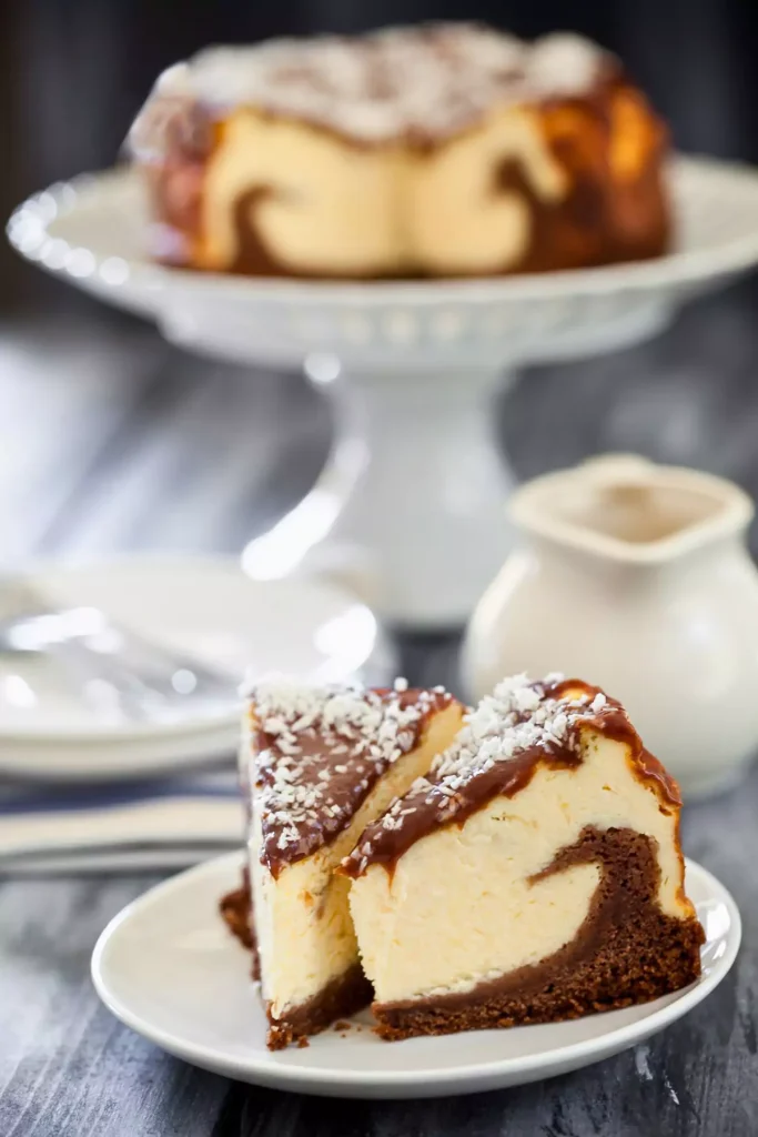 A rich, creamy Nutella cheesecake topped with toasted hazelnuts on an Oreo cookie crust, served on a white plate.