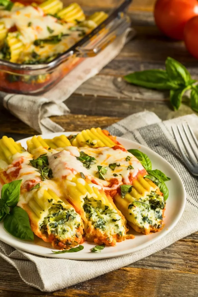 A plate of Spinach Chicken Manicotti, featuring creamy stuffed pasta shells topped with melted cheese, garnished with fresh parsley.