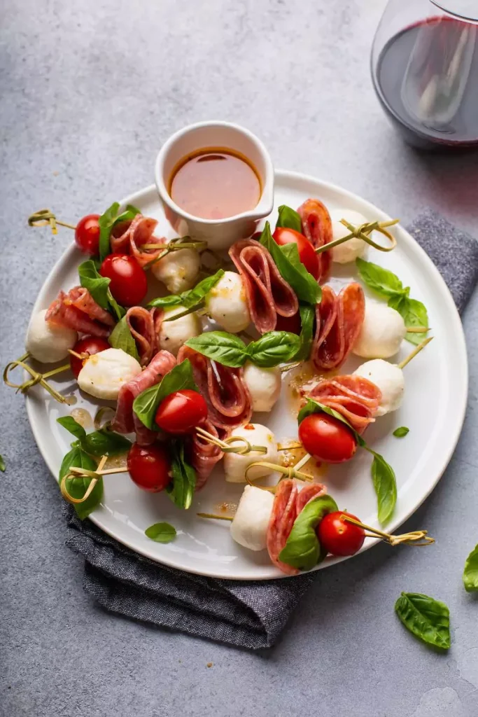 Close-up of colorful antipasto skewers with tortellini, olives, pepperoni, and salami arranged on a platter.