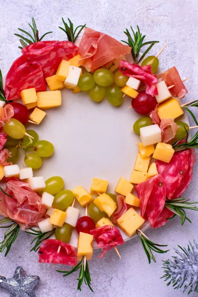 A festive appetizer wreath made from crescent rolls, topped with creamy cheese and fresh vegetables, arranged in a colorful ring