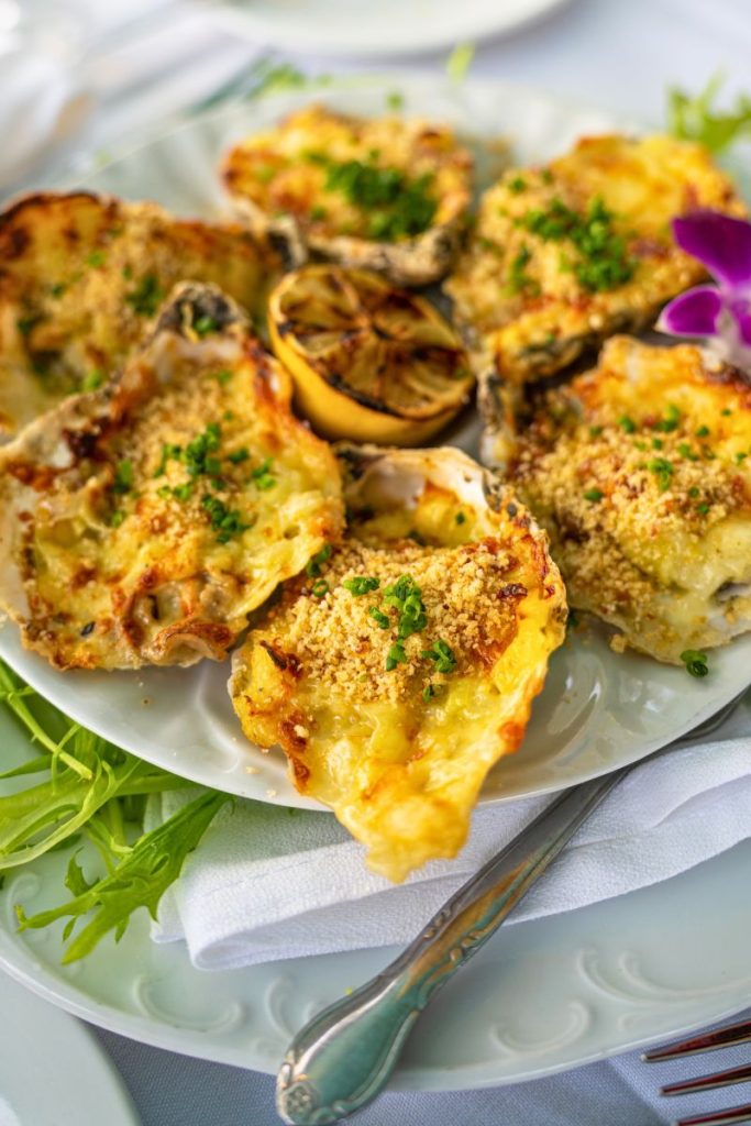 A serving of crispy baked oysters on a plate with a side of creamy jalapeño mayo dip and lemon wedges