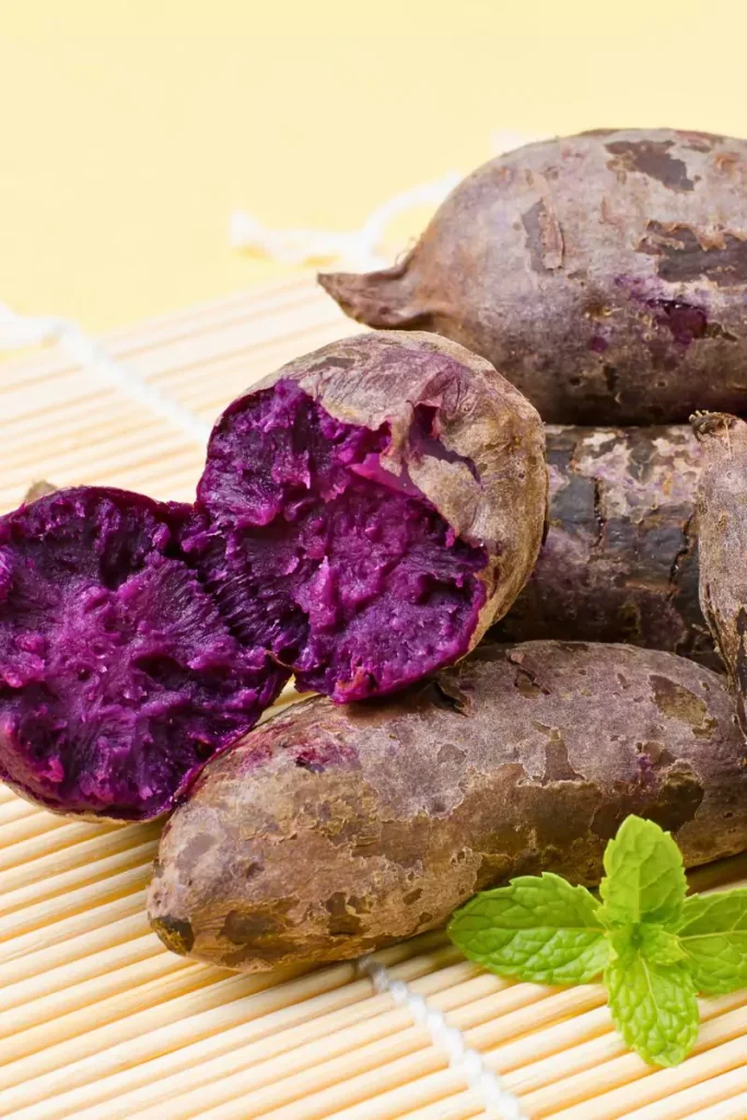 Roasted purple potatoes with balsamic vinegar and fresh herbs, garnished with basil leaves.