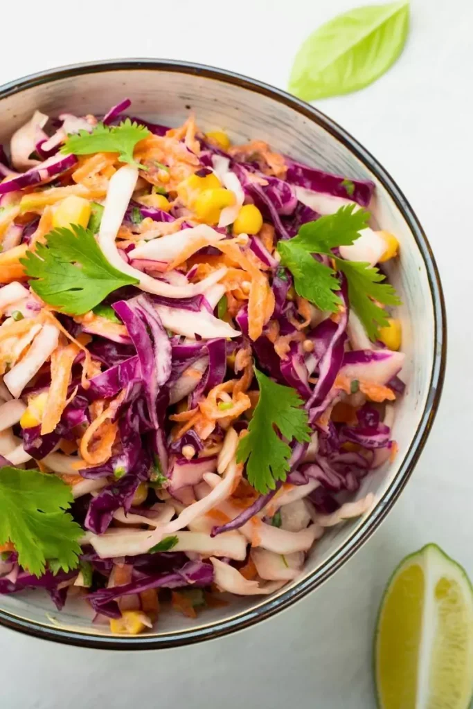 A vibrant cabbage salad with purple cabbage, green apple matchsticks, arugula, and toasted pecans, served in a large bowl.