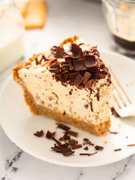 A slice of creamy Cannoli Cream Pie topped with mini chocolate chips on a dessert plate.