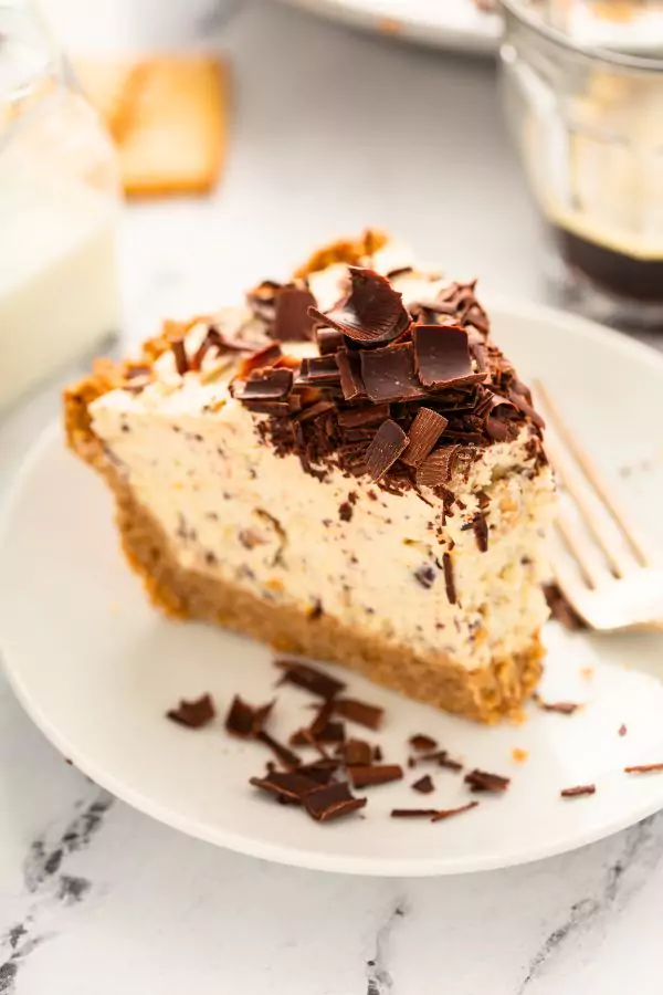 A slice of creamy Cannoli Cream Pie topped with mini chocolate chips on a dessert plate.