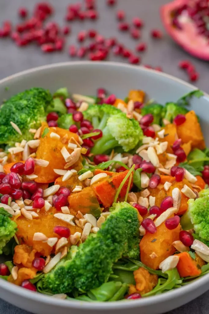 A festive Christmas pomegranate salad in a large bowl with leafy greens, pomegranate seeds, crumbled blue cheese, and walnuts, ready to serve.