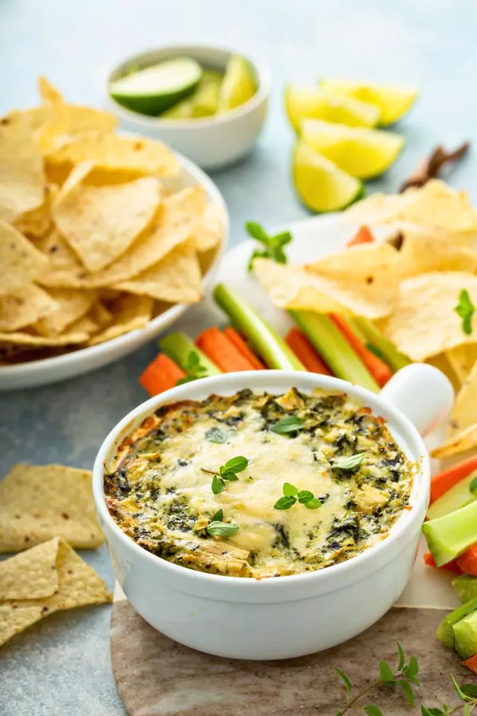 A warm and creamy holiday spinach dip in a dish, topped with a golden crust and served with crackers