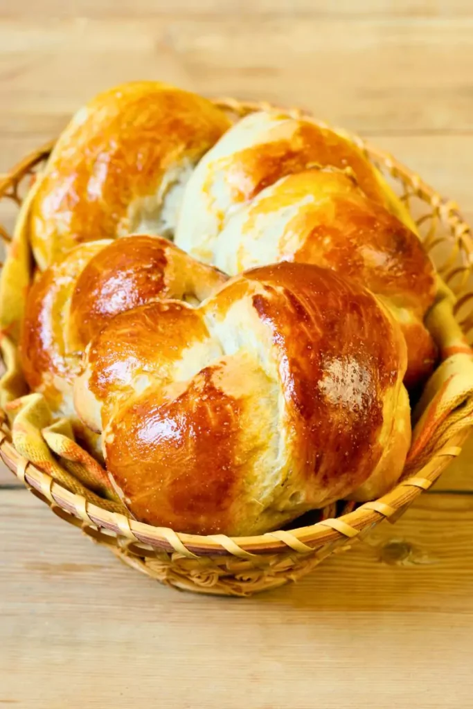 Golden brown honey whole wheat pan rolls brushed with honey glaze in a pan with a side of honey butter