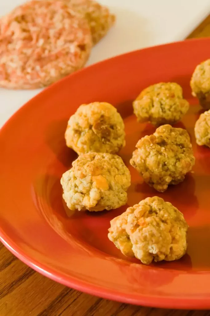 Golden-brown sausage balls arranged on a plate, showcasing their cheesy, savory texture